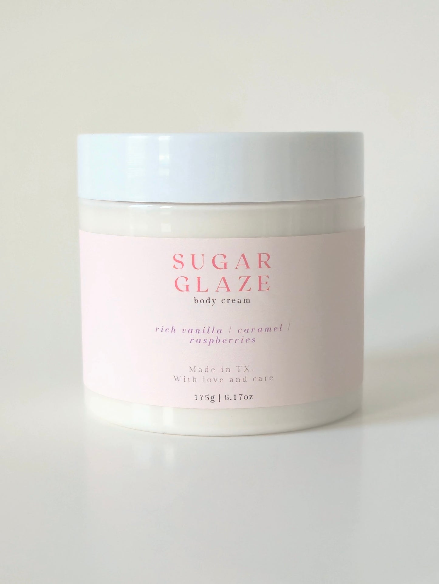Sugar Glaze body cream in a 175g plastic jar. Rich, sweet-scented cream with notes of caramel, vanilla, and raspberry. Dessert-inspired body care.