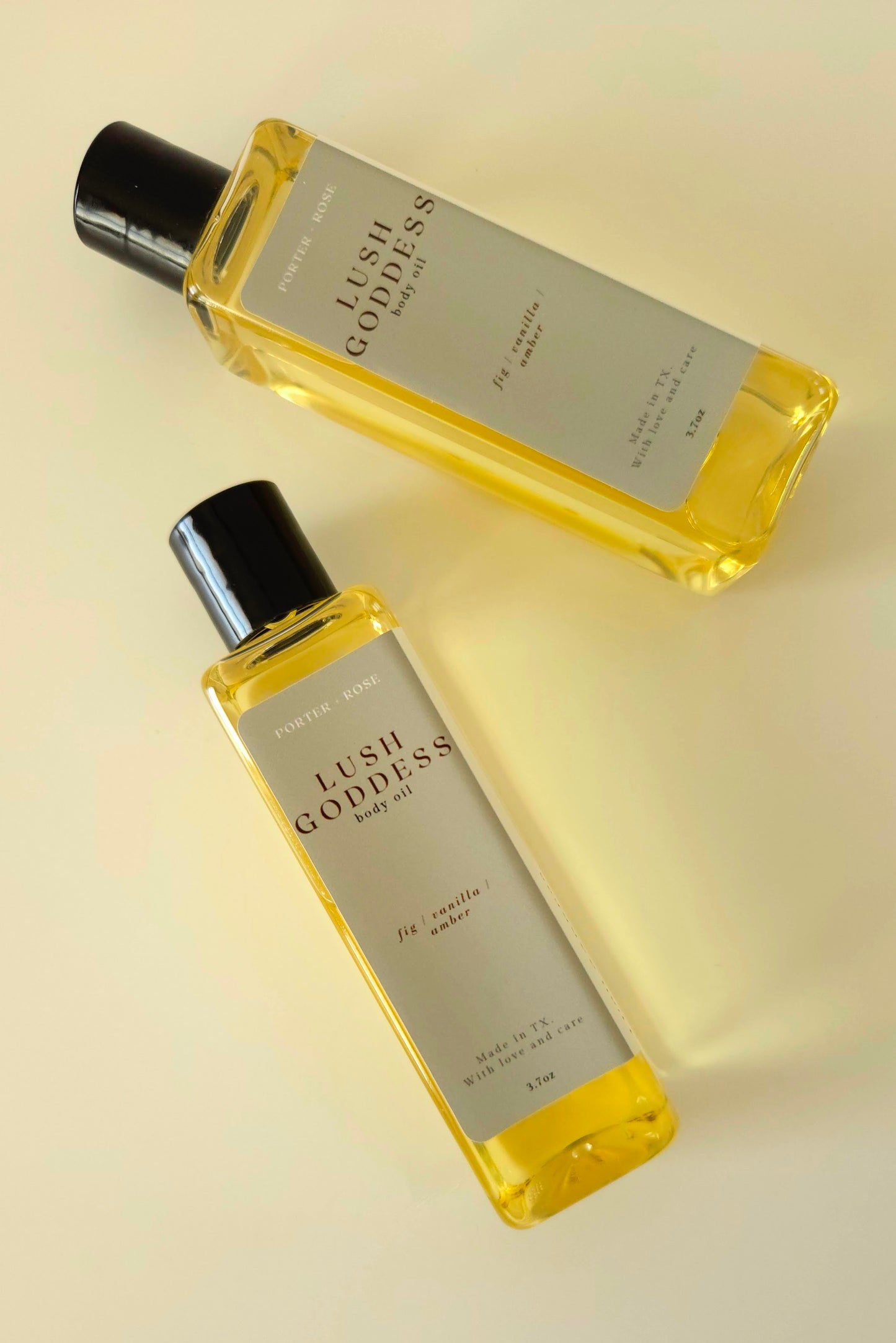 Lush Goddess body oil in a rectangular plastic bottle, styled with fig, honey, and greenery to reflect the scent's earthy, sweet profile.
