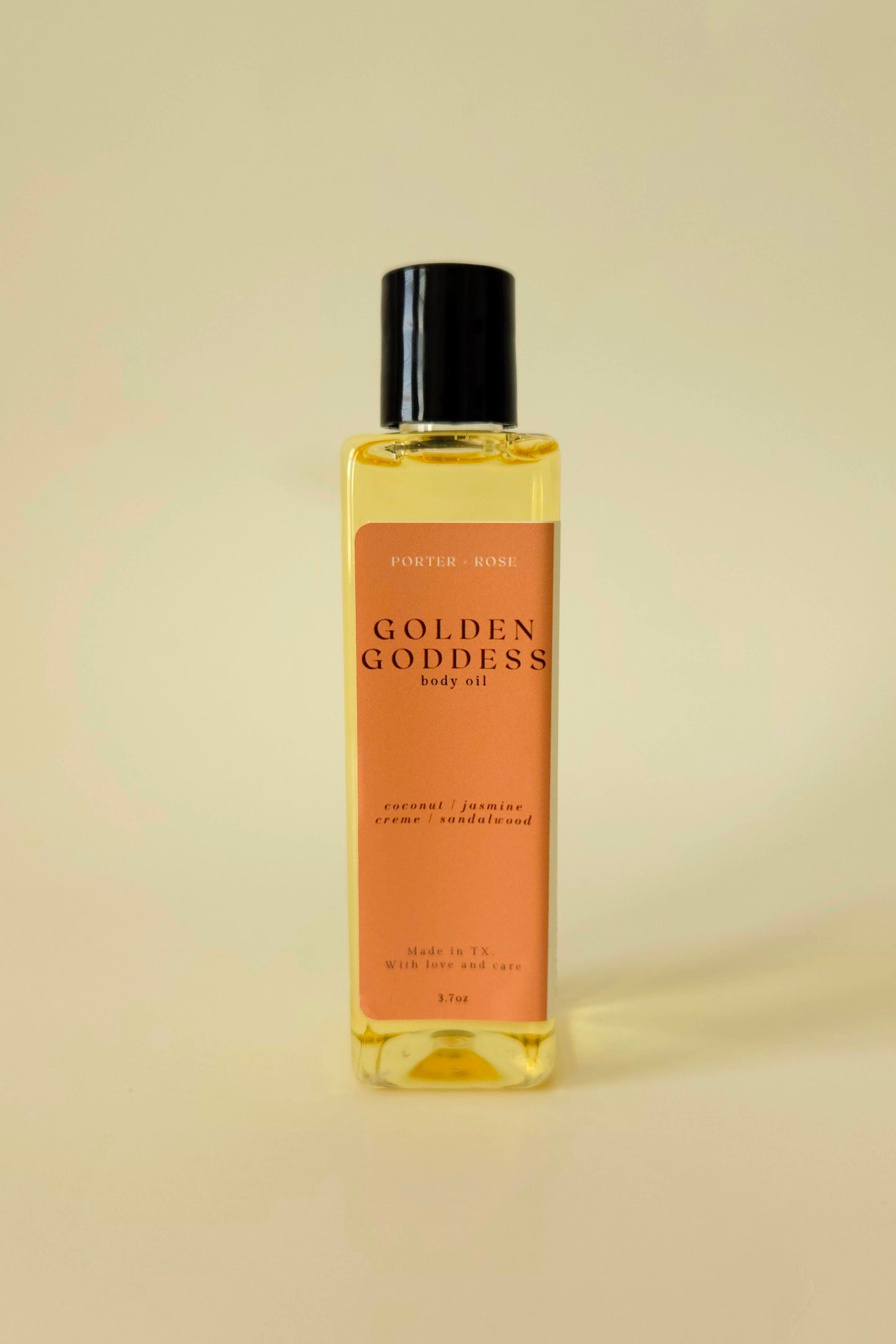 Golden Goddess body oil in a sleek rectangular bottle, styled with coconut, pistachio, and amber tones to reflect its warm, sweet scent.