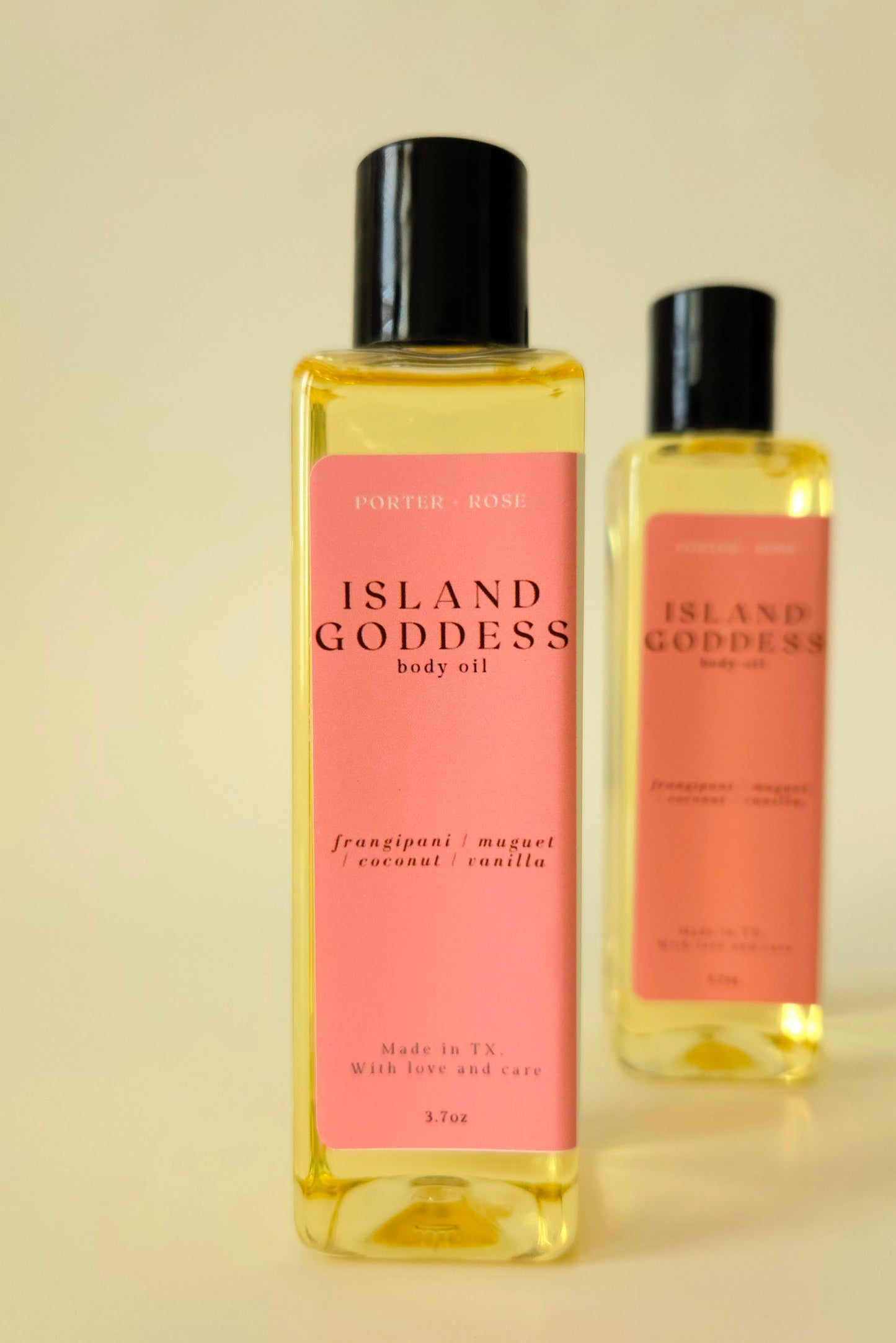 Island Goddess body oil in a clear rectangular bottle, styled with tropical flowers and coconut to reflect its creamy, floral scent.