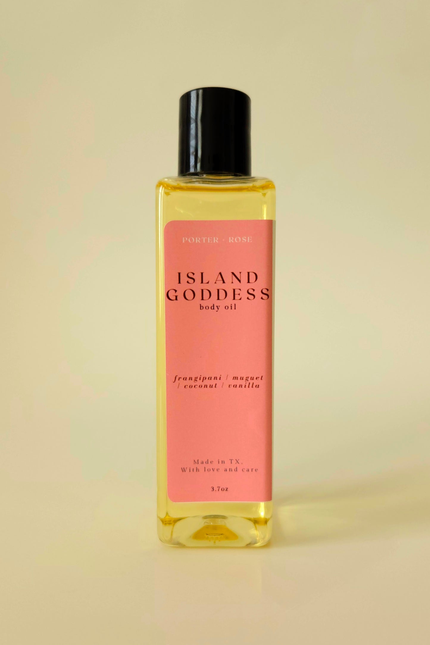 Island Goddess body oil in a clear rectangular bottle, styled with tropical flowers and coconut to reflect its creamy, floral scent.
