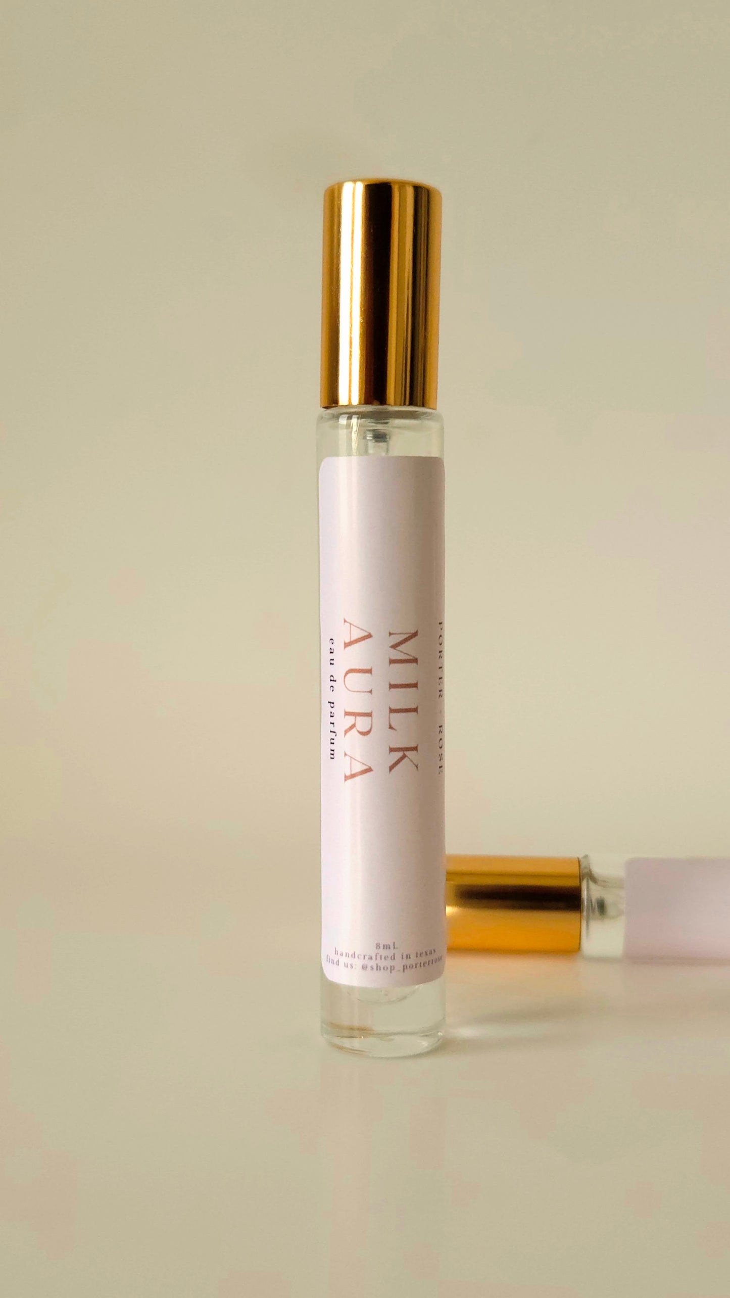 Roll-on bottle with gold cap and white label on a beige background
