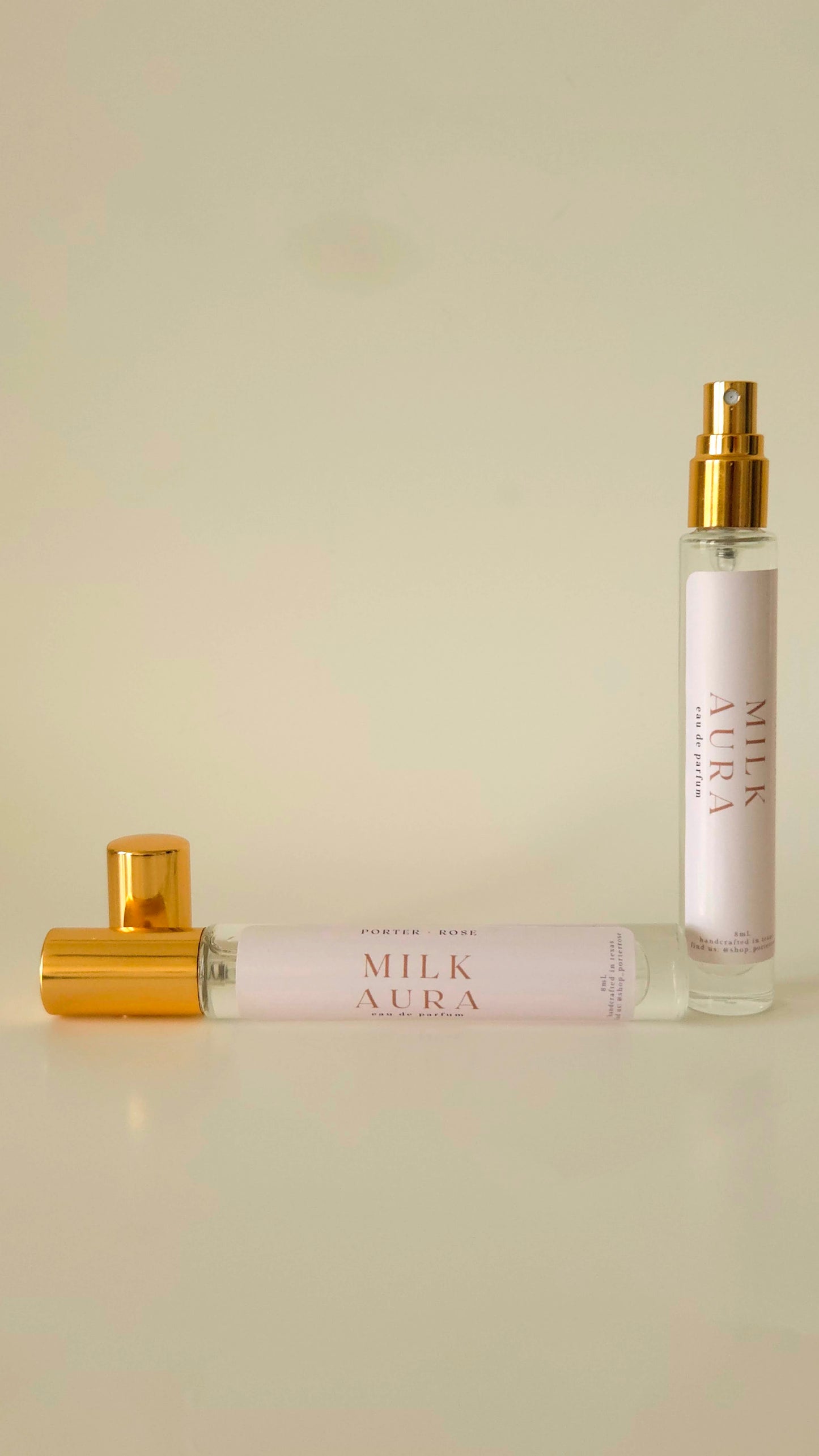 Two Milk Aura perfume bottles on a light beige background
