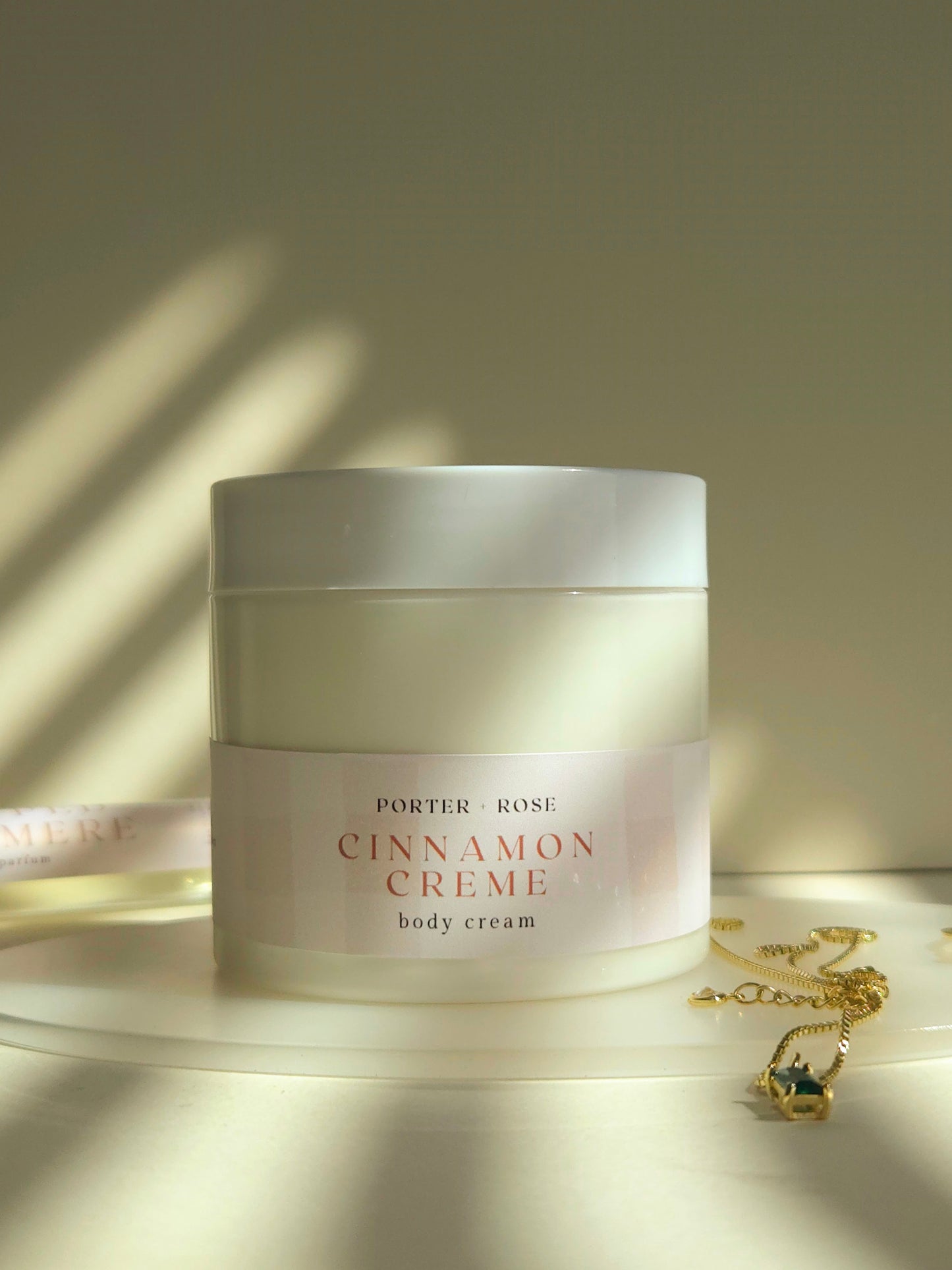 Jar of Porter & Rose Cinnamon Crème body cream on a wooden surface with soft lighting.
