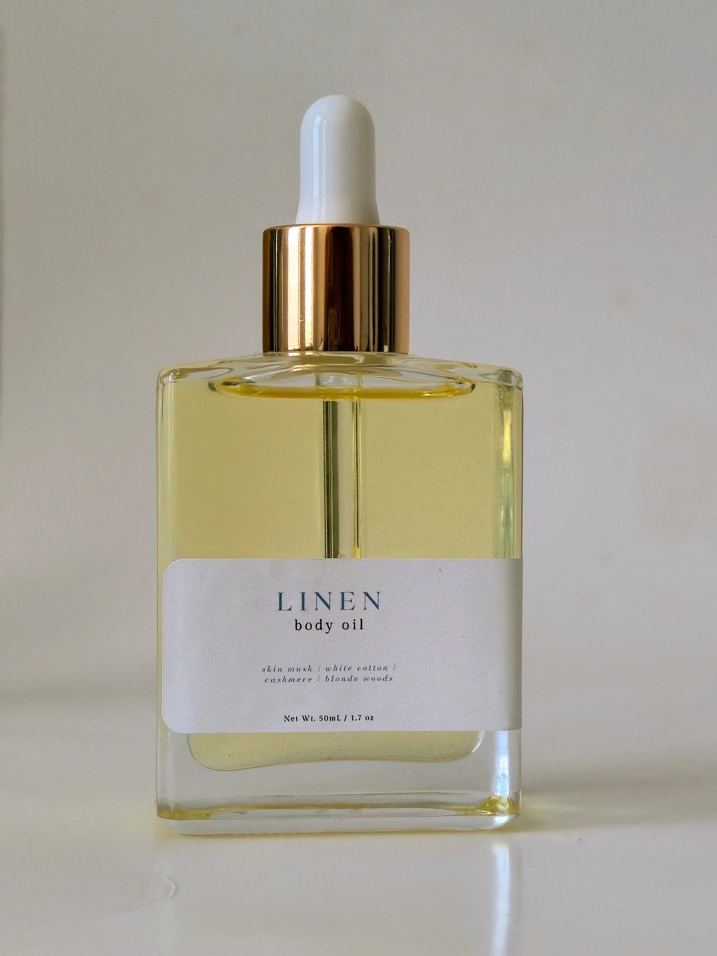 Bottle of Linen body oil with a dropper on a light background