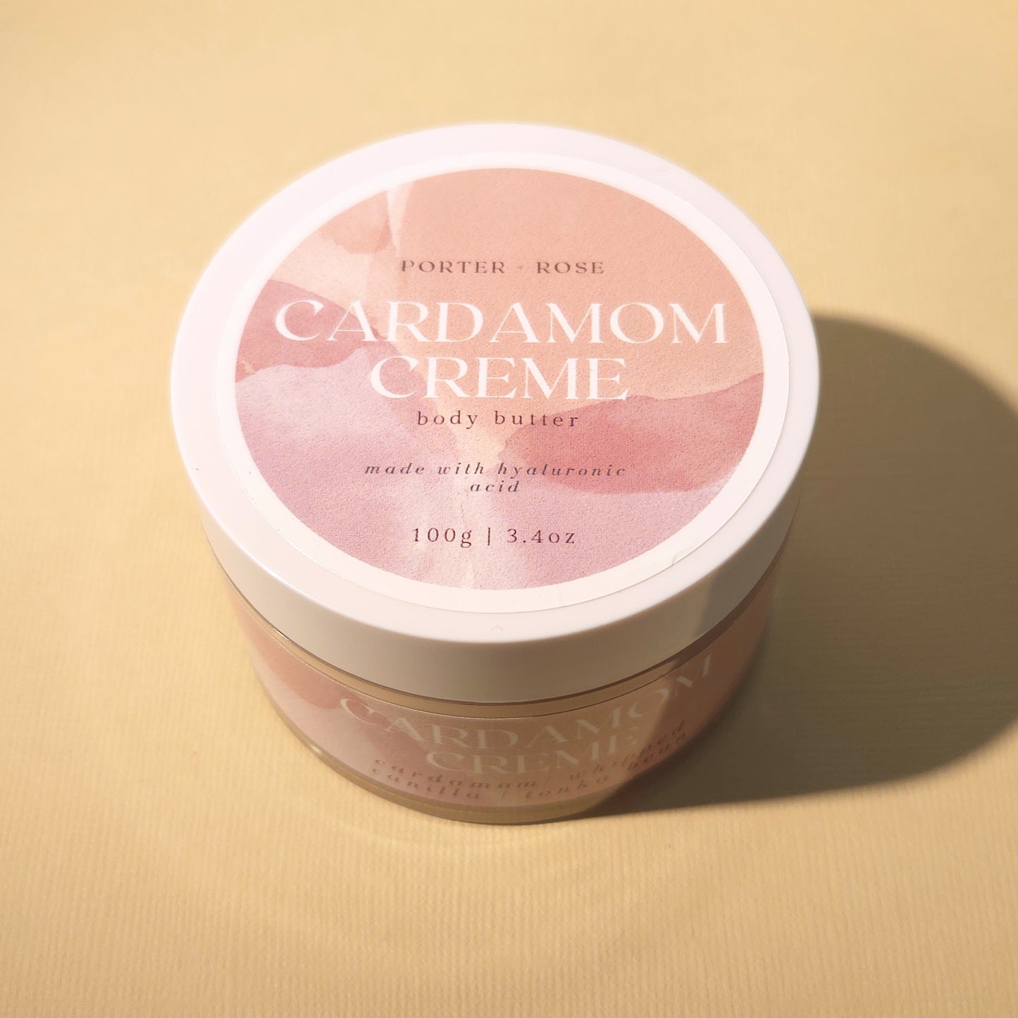 Cardamom Cream Body Butter in a clear plastic jar with a white lid. Luxurious, hydrating body butter for soft, smooth skin.