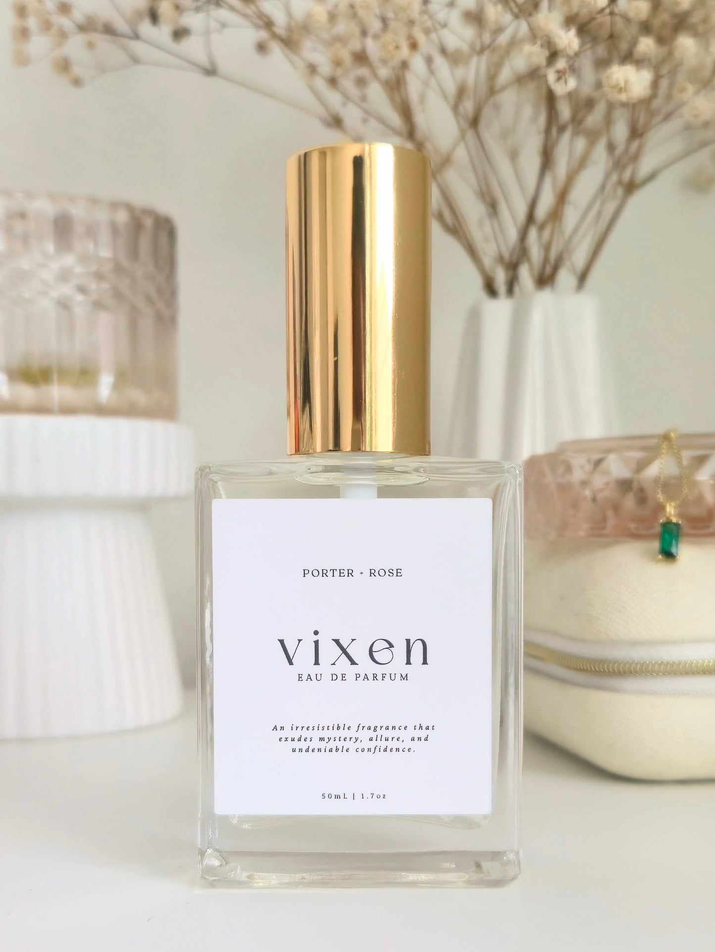 Vixen perfume bottle with gold cap on a white surface with decorative elements