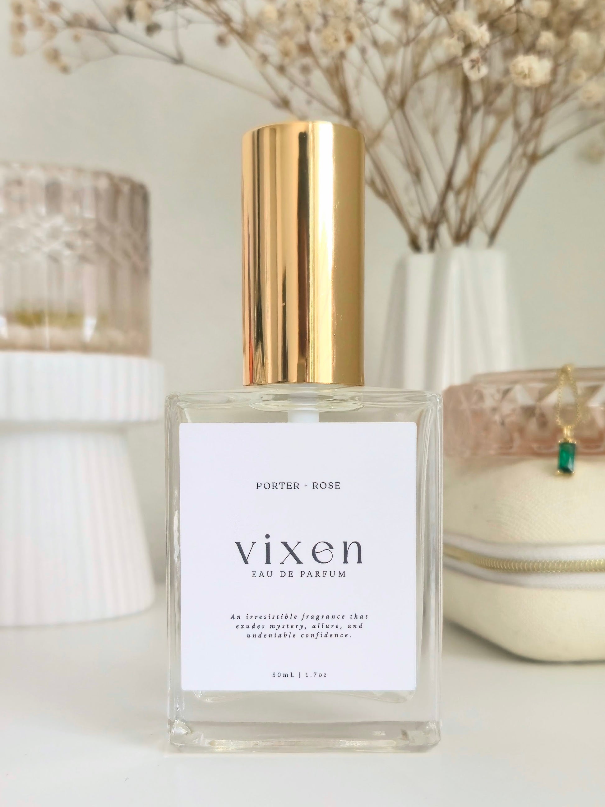 Vixen perfume bottle with gold cap on a white surface with decorative elements