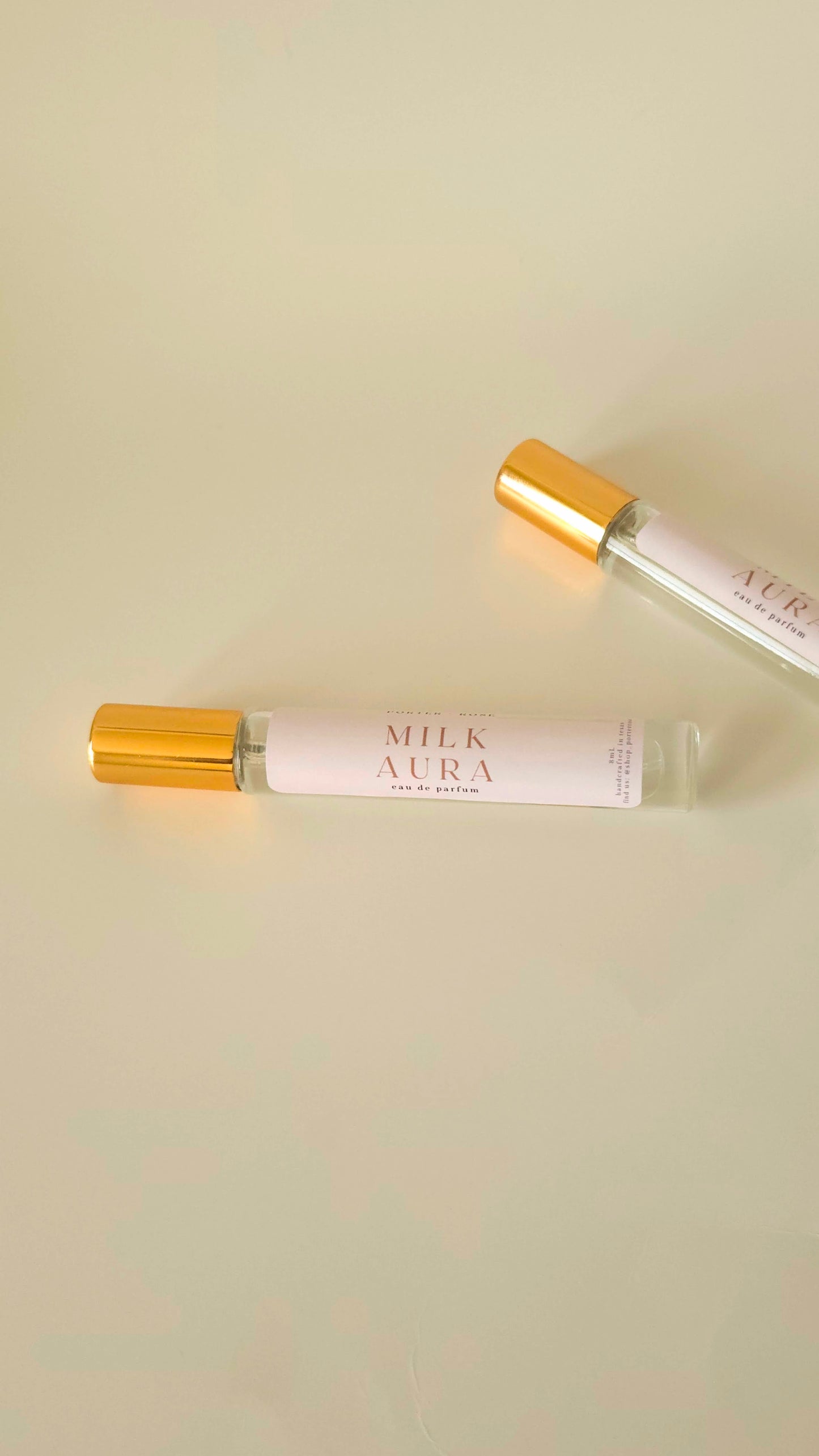 Two 'Milk Aura' eau de parfums tubes on a beige background