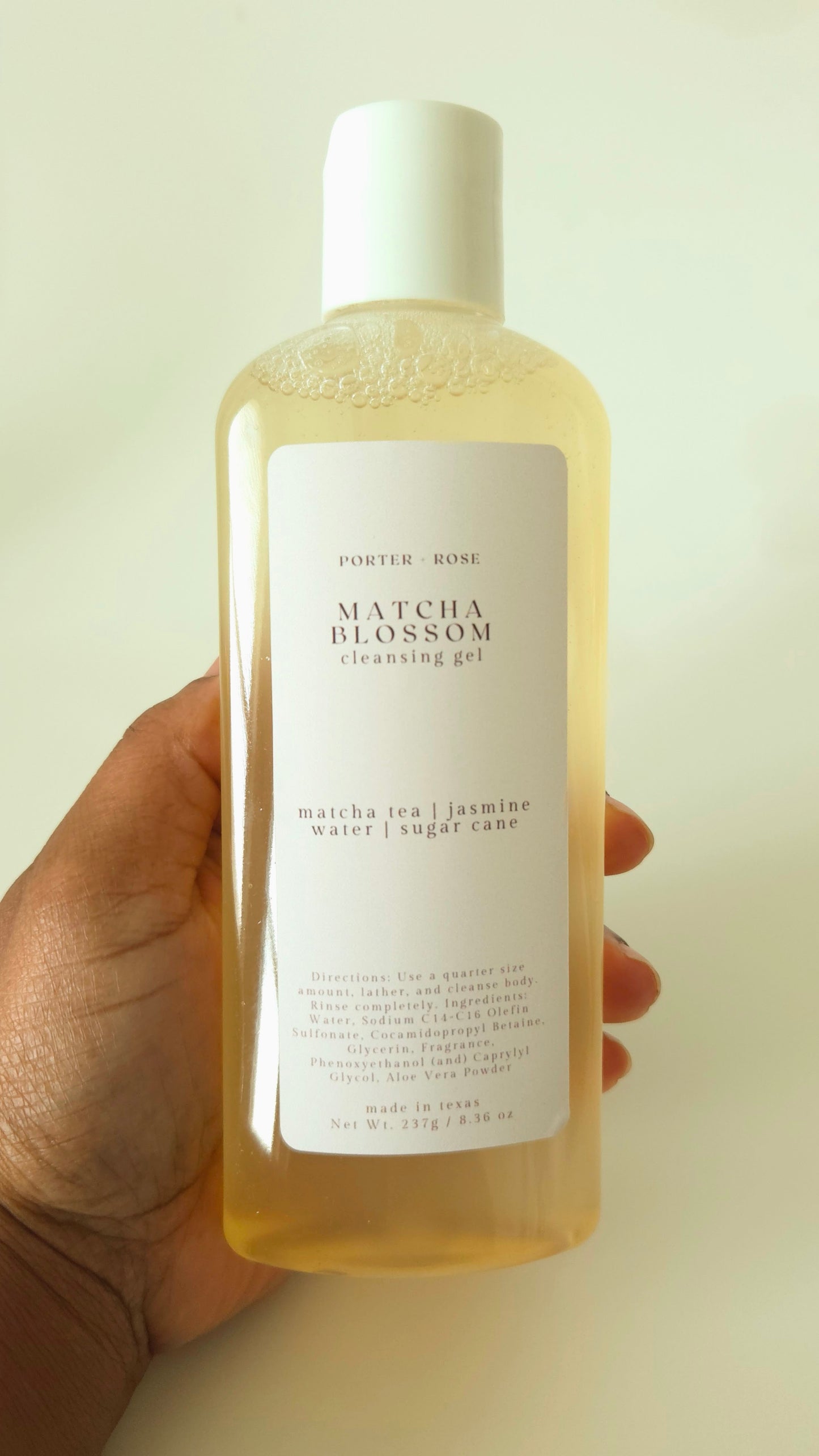 Hand holding a bottle of Matcha Blossom cleansing gel with a white label.