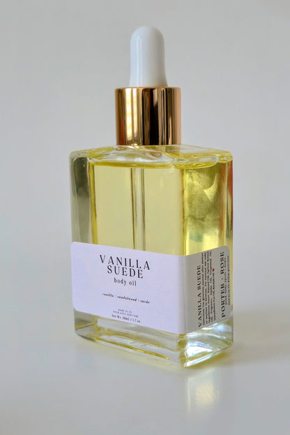 Bottle of Vanilla Suede body oil with a gold cap on a white background