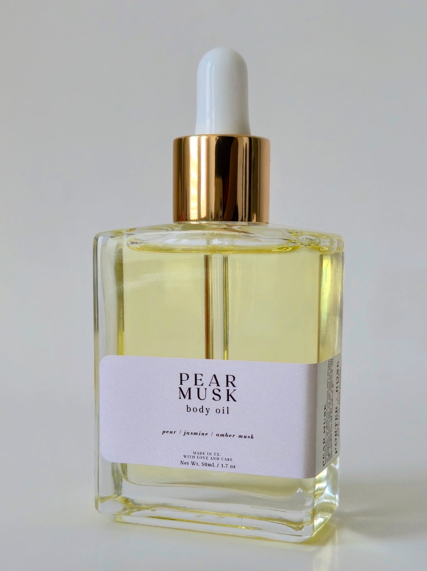 Bottle of Pear Musk body oil on a light gray background