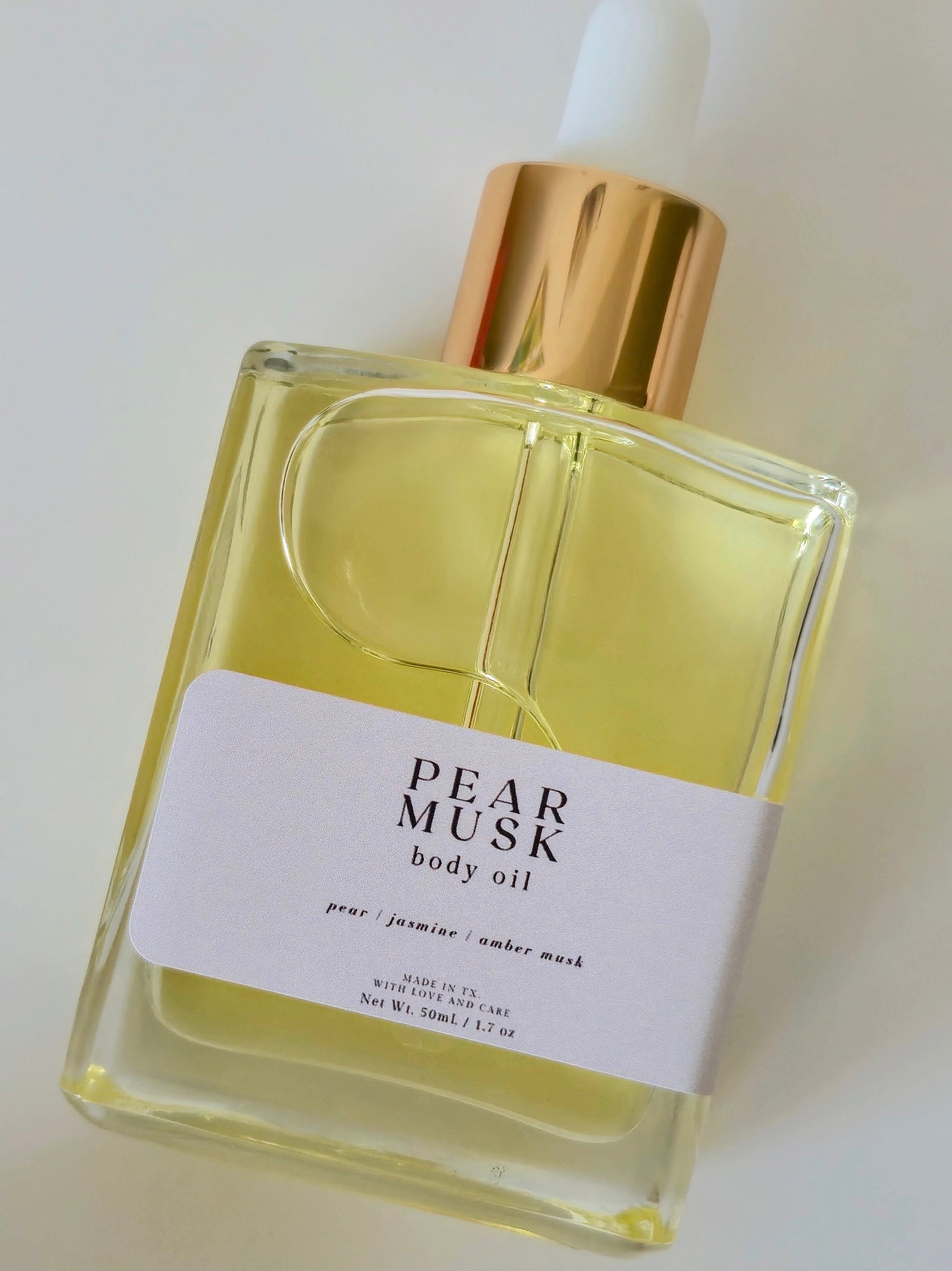 Bottle of Pear Musk body oil with a gold cap on a white background