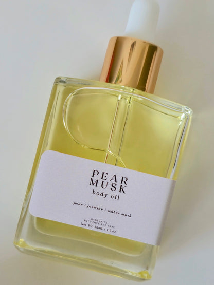 Bottle of Pear Musk body oil with a gold cap on a white background