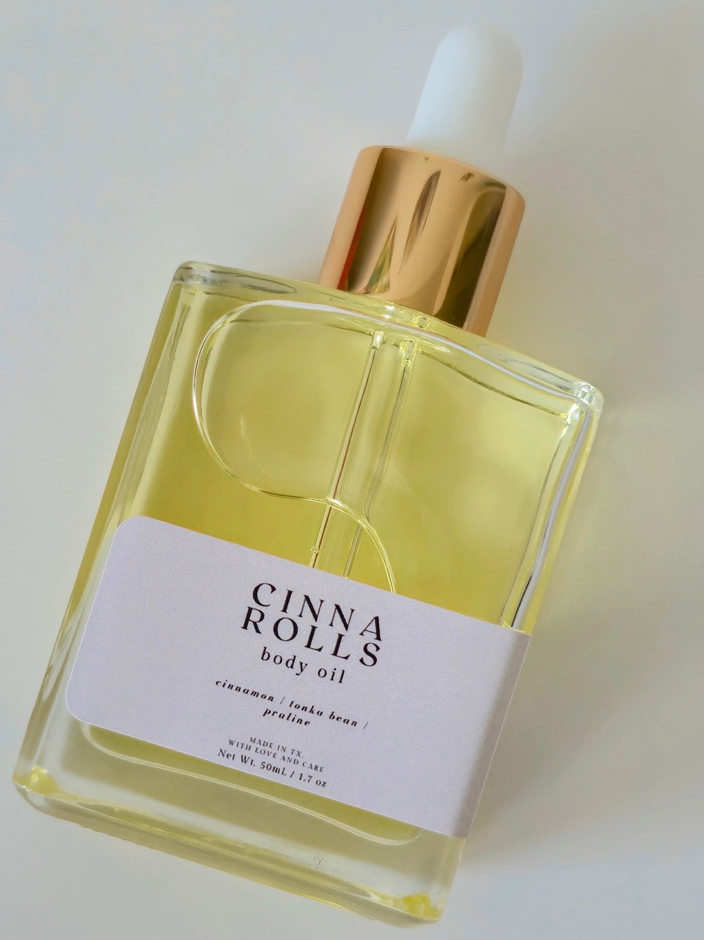 Bottle of Cinna Rolls body oil with a white background