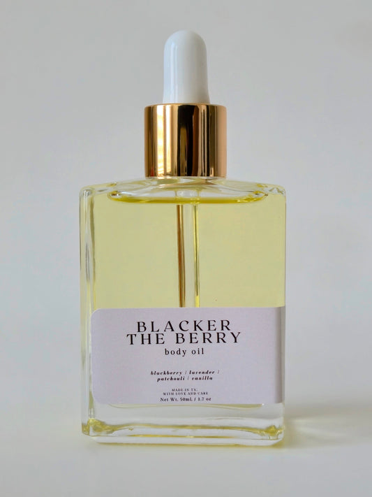 Glass bottle of Blacker The Berry body oil with a white dropper on a light gray background