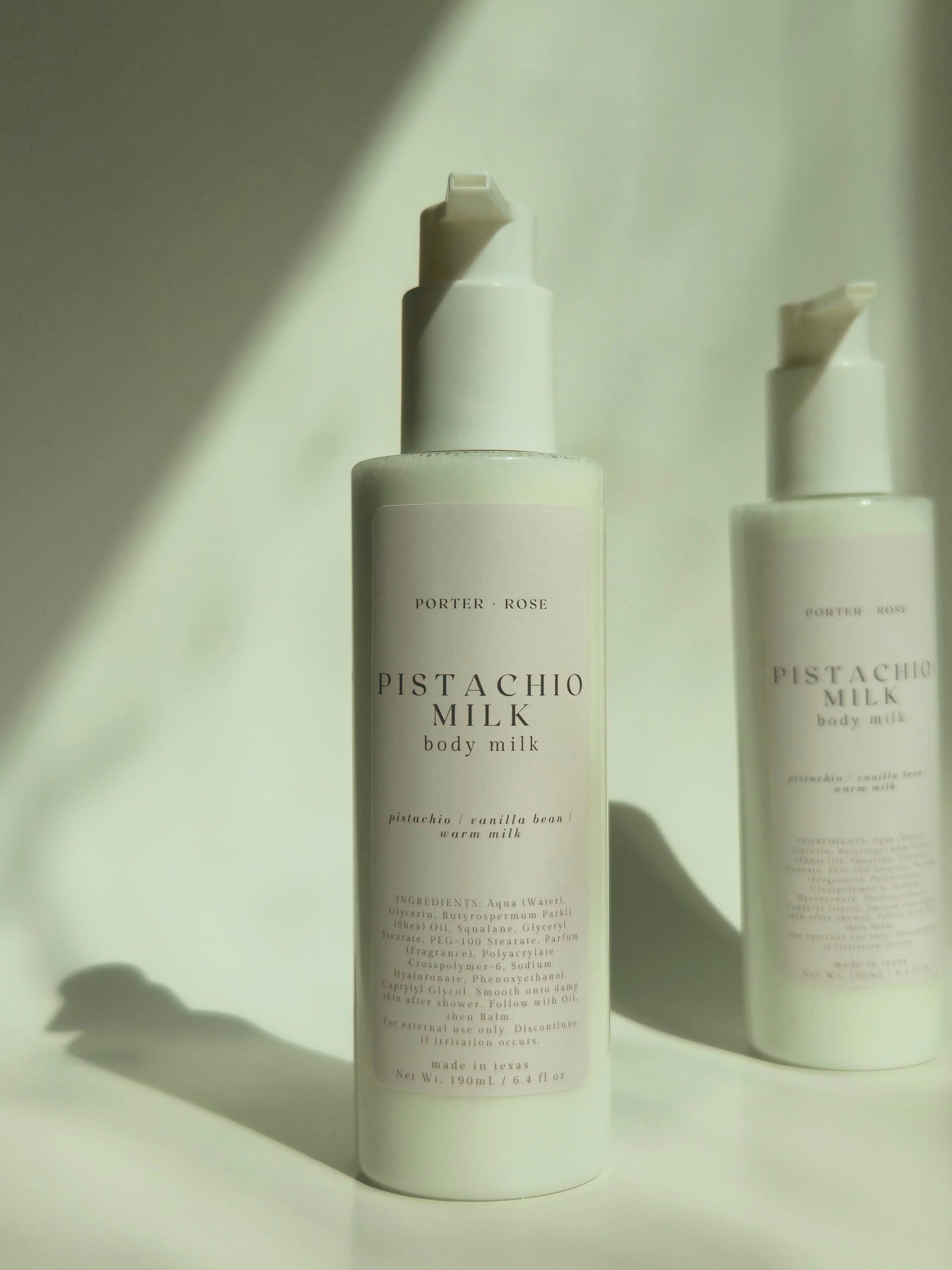 Two bottles of Pistachio Milk body milk by Porter & Rose on a light background