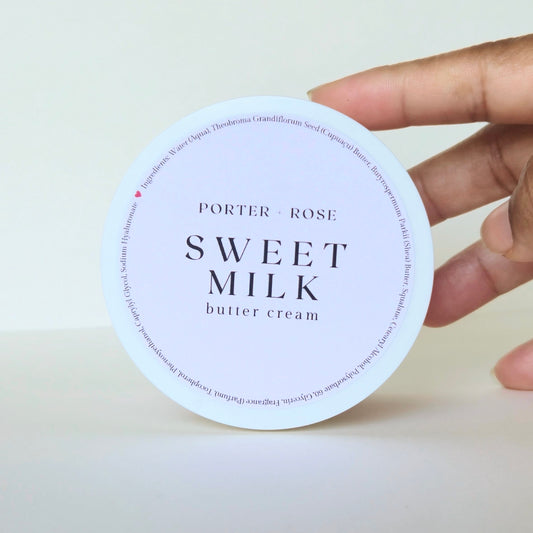 Hand holding a container of Porter & Rose Sweet Milk butter cream against a white background