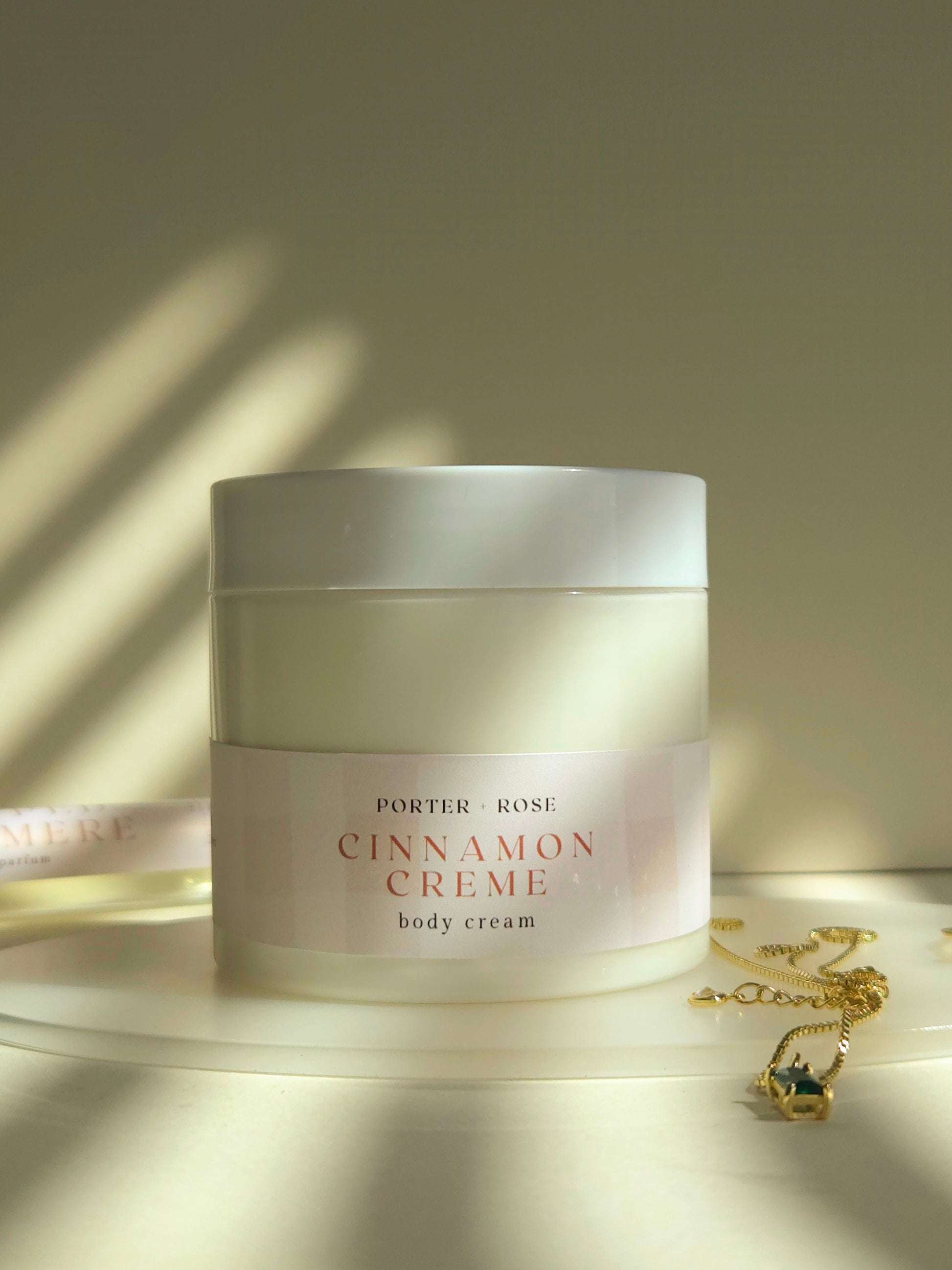 Jar of Porter & Rose Cinnamon Crème body cream on a wooden surface with soft lighting.
