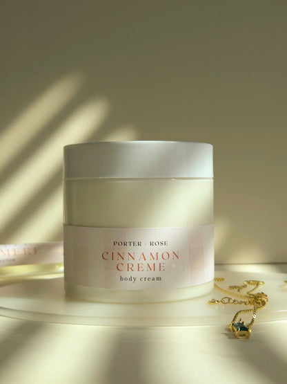 Jar of Porter & Rose Cinnamon Crème body cream on a wooden surface with soft lighting.