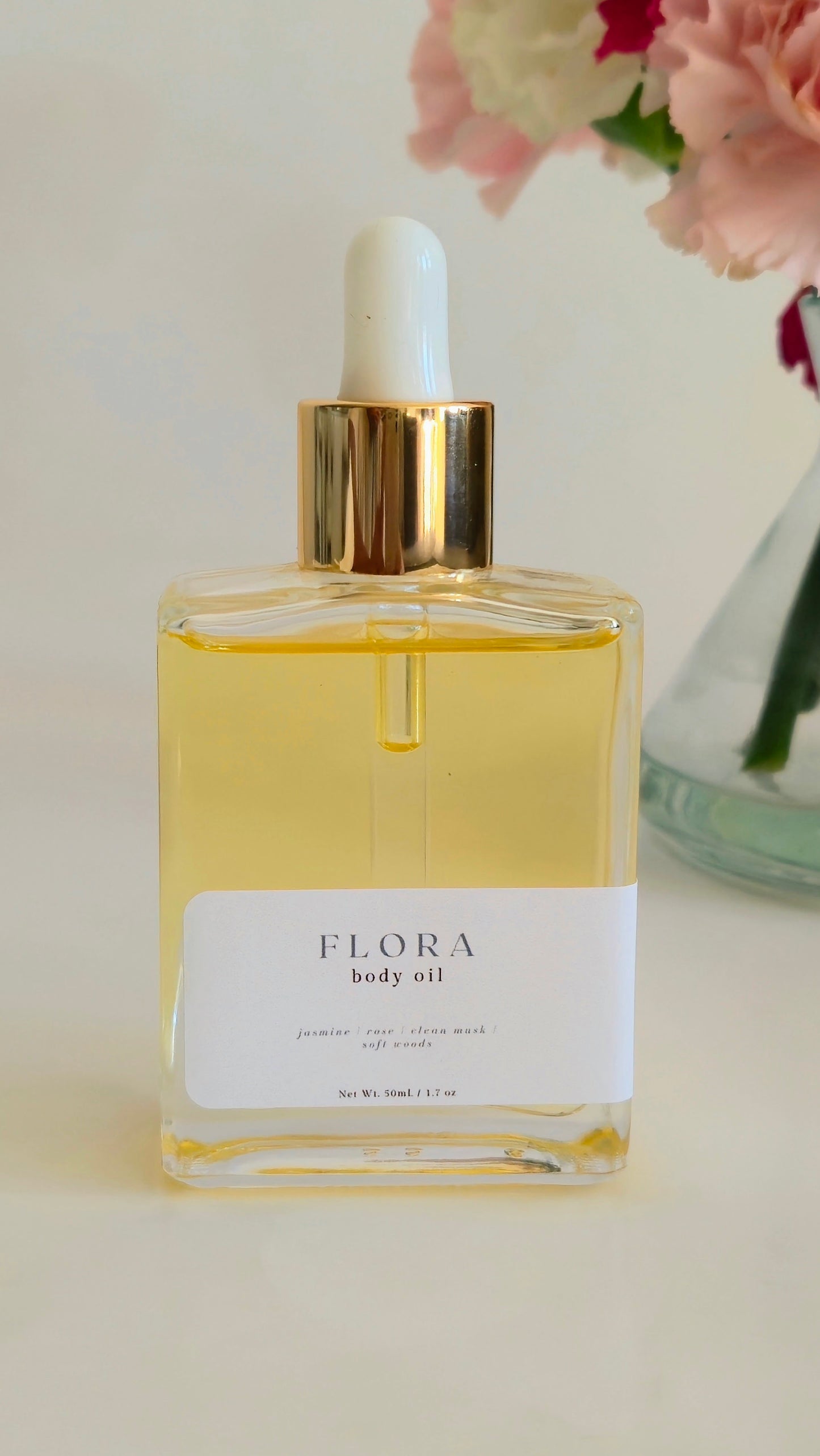 Flora body oil bottle with dropper on a light background