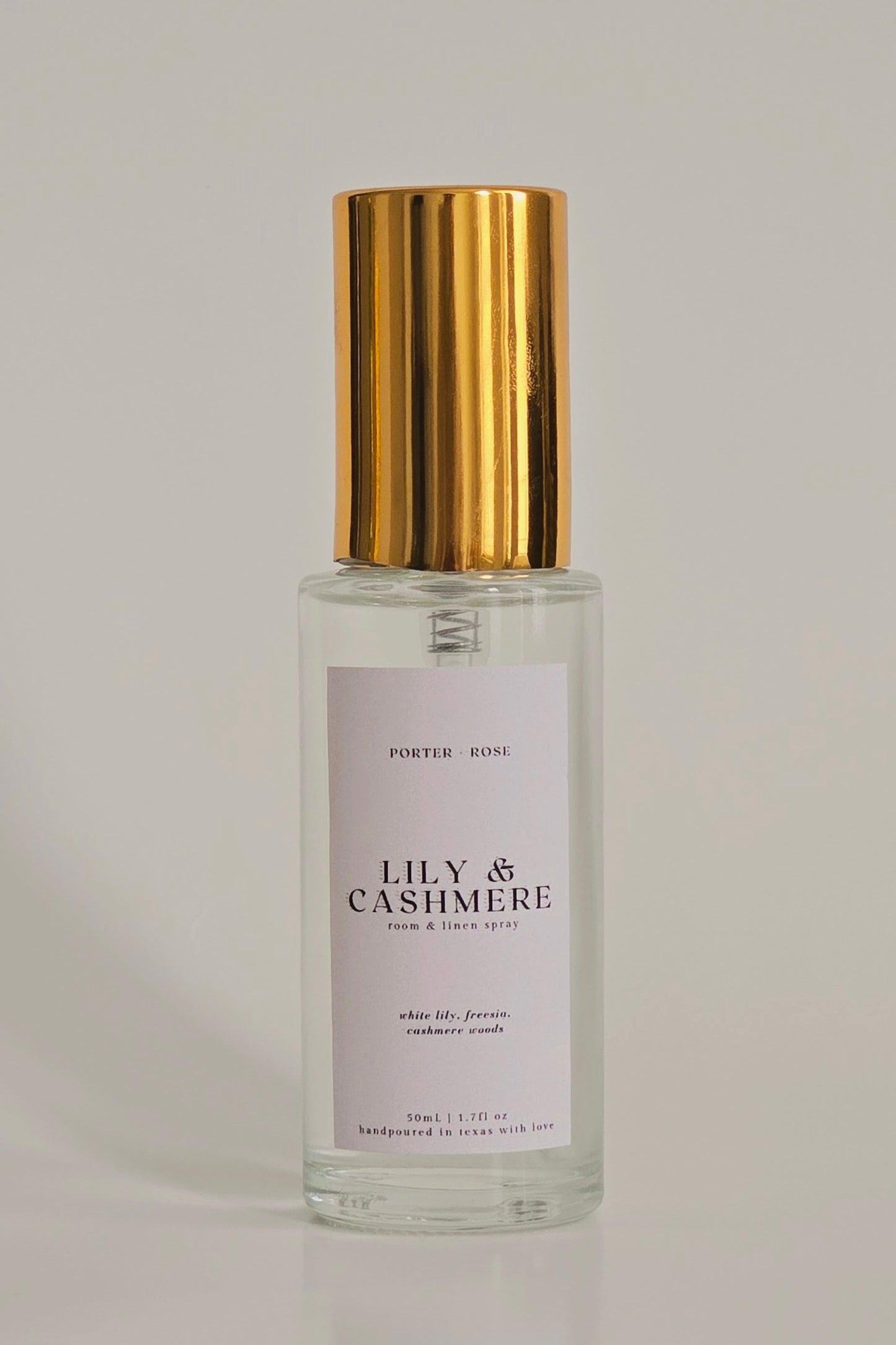 Perfume bottle with gold cap and white label on a gray background