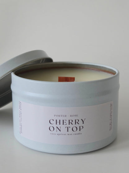 Wooden Wick Candle in a tin labeled 'Cherry on Top' on a neutral background