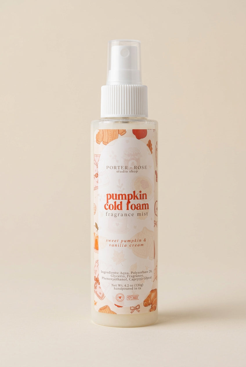A bottle of Porter & Rose Pumpkin Cold Foam fragrance mist on a warm beige background. The bottle is frosted with a white spray top and features a label decorated with orange pumpkins and illustrations of vanilla beans.