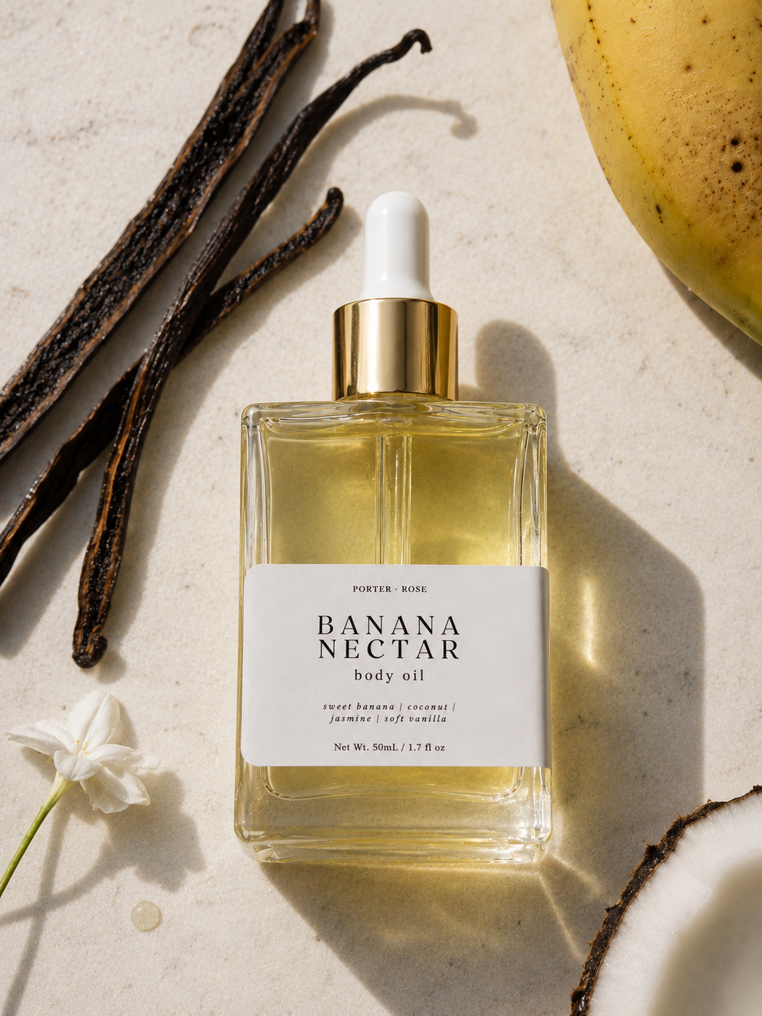 Bottle of Banana Nectar body oil with vanilla beans and a flower on a light background