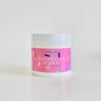 Jar of 'Birthday Cake' scented body butter with a pink label on a white background