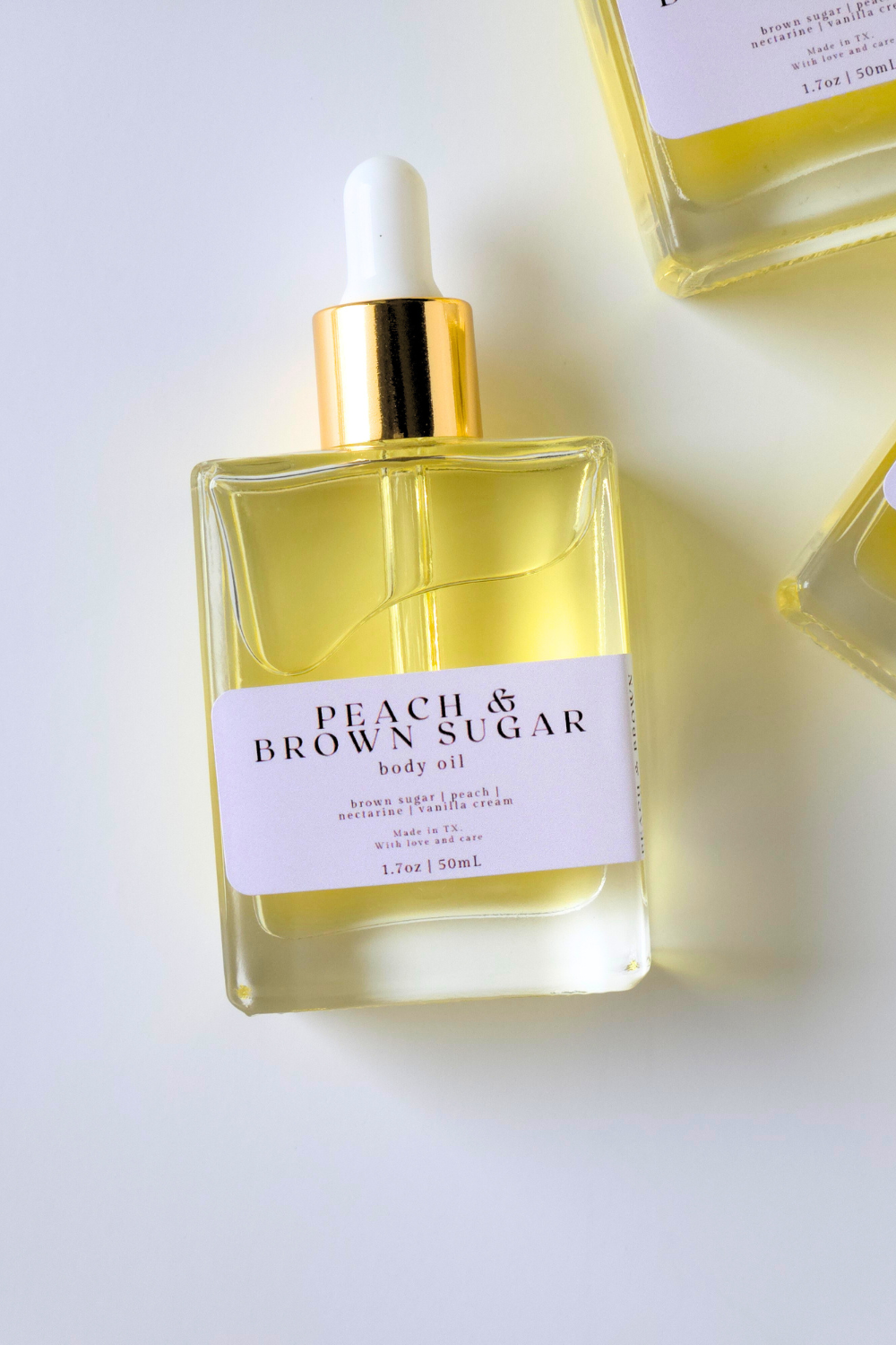 Body oil bottle labeled 'Peach & Brown Sugar' on a white background