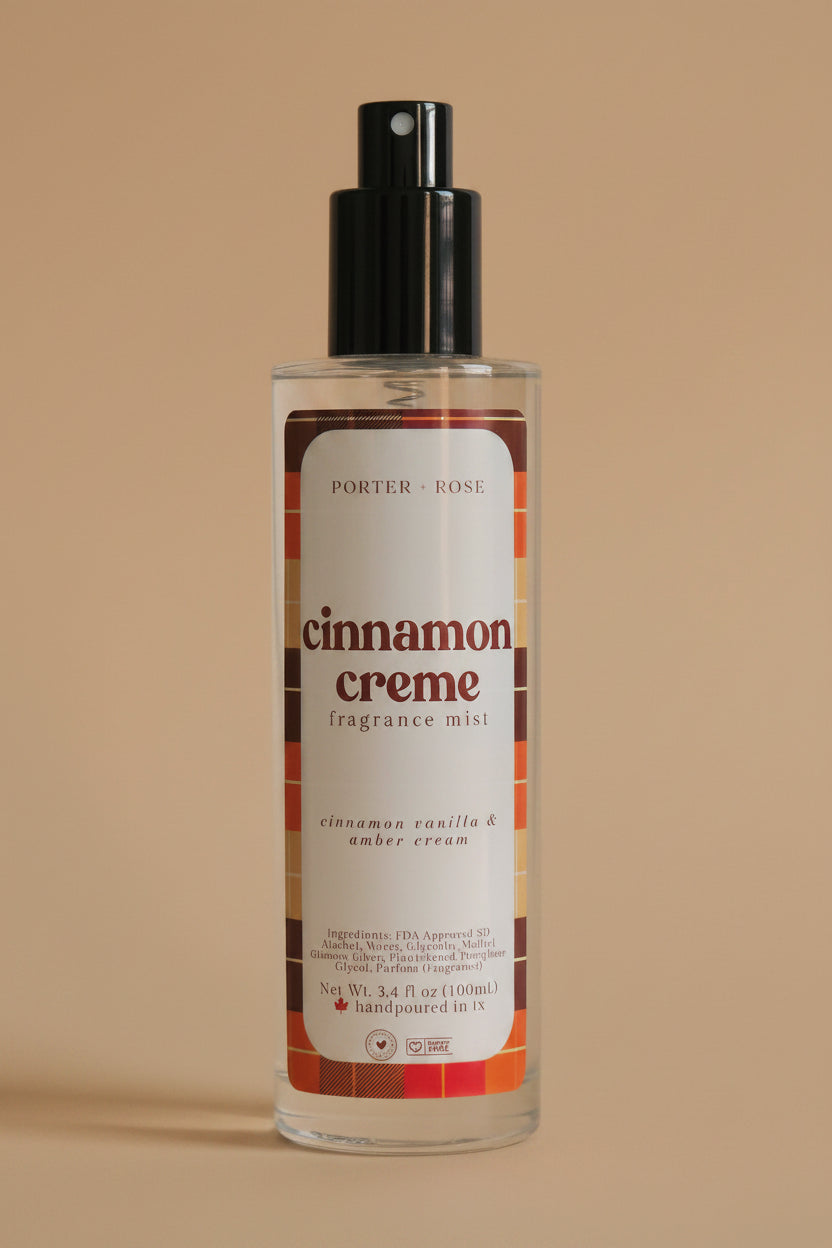A bottle of Porter Rose Cinnamon Creme Fragrance Oil with a black spray nozzle and a white label featuring red and brown text, set against a plain light gray background.