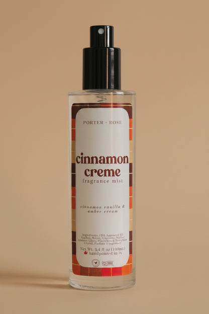 A bottle of Porter Rose Cinnamon Creme Fragrance Oil with a black spray nozzle and a white label featuring red and brown text, set against a plain light gray background.