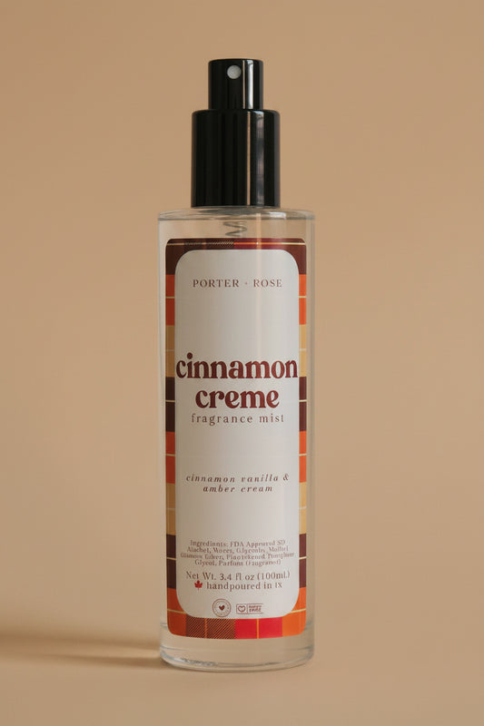 A bottle of Porter Rose Cinnamon Creme Fragrance Oil with a black spray nozzle and a white label featuring red and brown text, set against a plain light gray background.