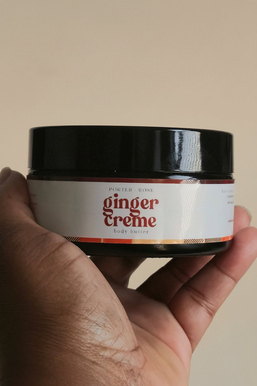 hand holding black jar of ginger creme body butter by porter + rose