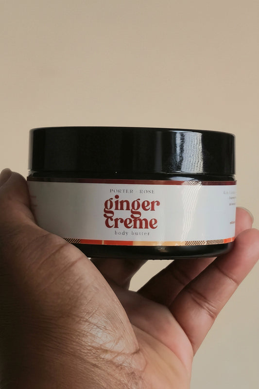 hand holding black jar of ginger creme body butter by porter + rose