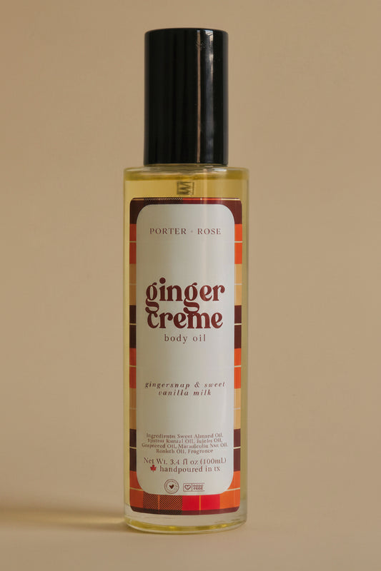 A bottle of Porter Rose Ginger Creme body oil with a black cap and a cream-colored label featuring red and orange accents, set against a plain light gray background.