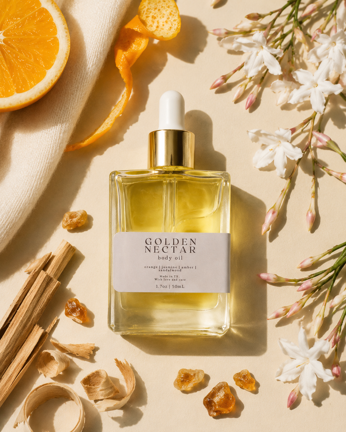 Bottle of Golden Nectar body oil with orange, sandalwood, amber resin, and jasmine flowers on a beige background