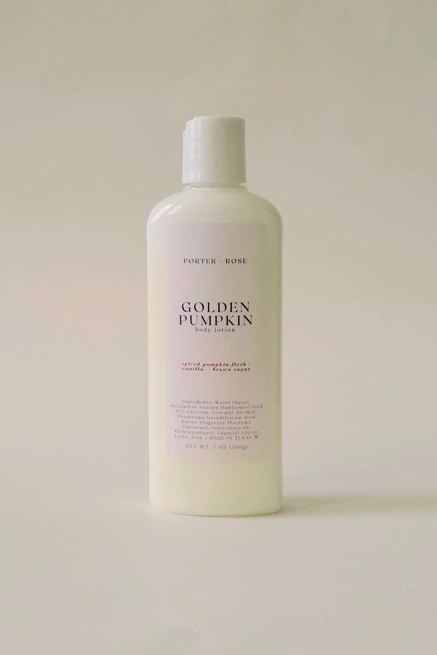 A white plastic bottle of Porter Rose Golden Pumpkin body lotion, featuring a minimalist white label with black text, set against a solid off-white background.