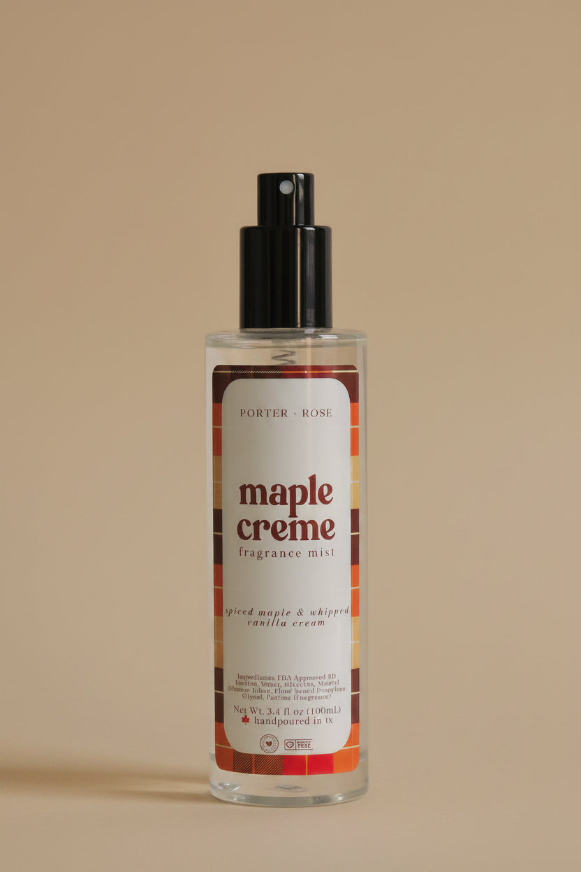 A clear cylindrical bottle of Porter's Rose Maple Creme body mist with a black spray nozzle, shown on a light gray background with its black cap placed below it.