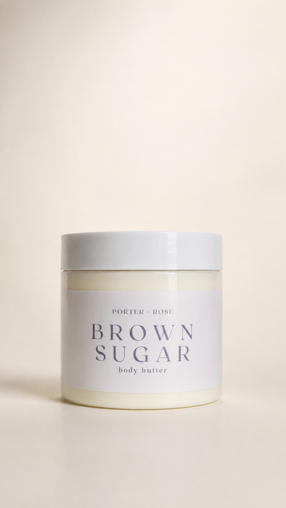 A jar of porter ROSE Brown Sugar body butter, featuring a white label with dark gray text and a matching white lid, set against a warm cream background.