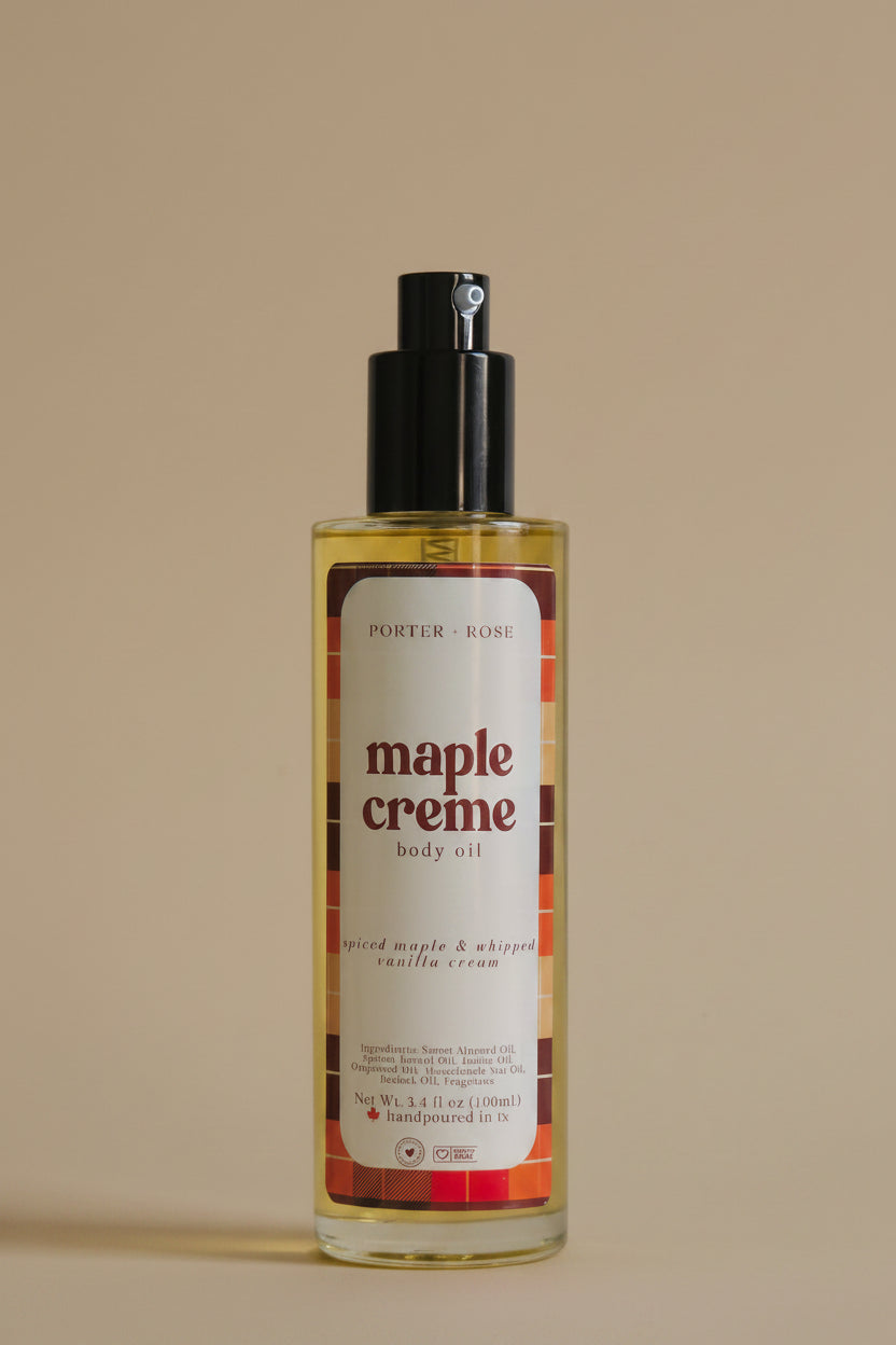 A bottle of Porter Rose Maple Creme Body Oil with a black pump dispenser and a white label featuring red and orange text, set against a plain light gray background.