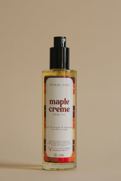 A bottle of Porter Rose Maple Creme Body Oil with a black pump dispenser and a white label featuring red and orange text, set against a plain light gray background.