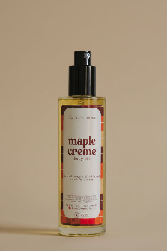 A bottle of Porter Rose Maple Creme Body Oil with a black pump dispenser and a white label featuring red and orange text, set against a plain light gray background.